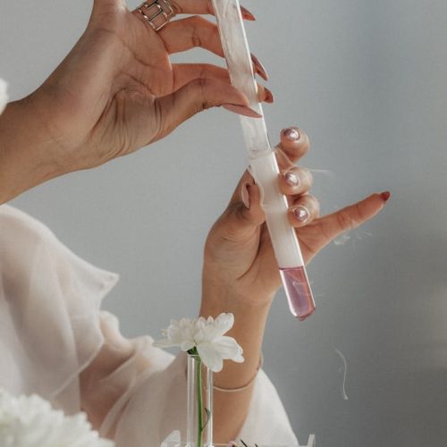 Woman with Manicure Holding Test Tubes, and White Flowers in the Glass